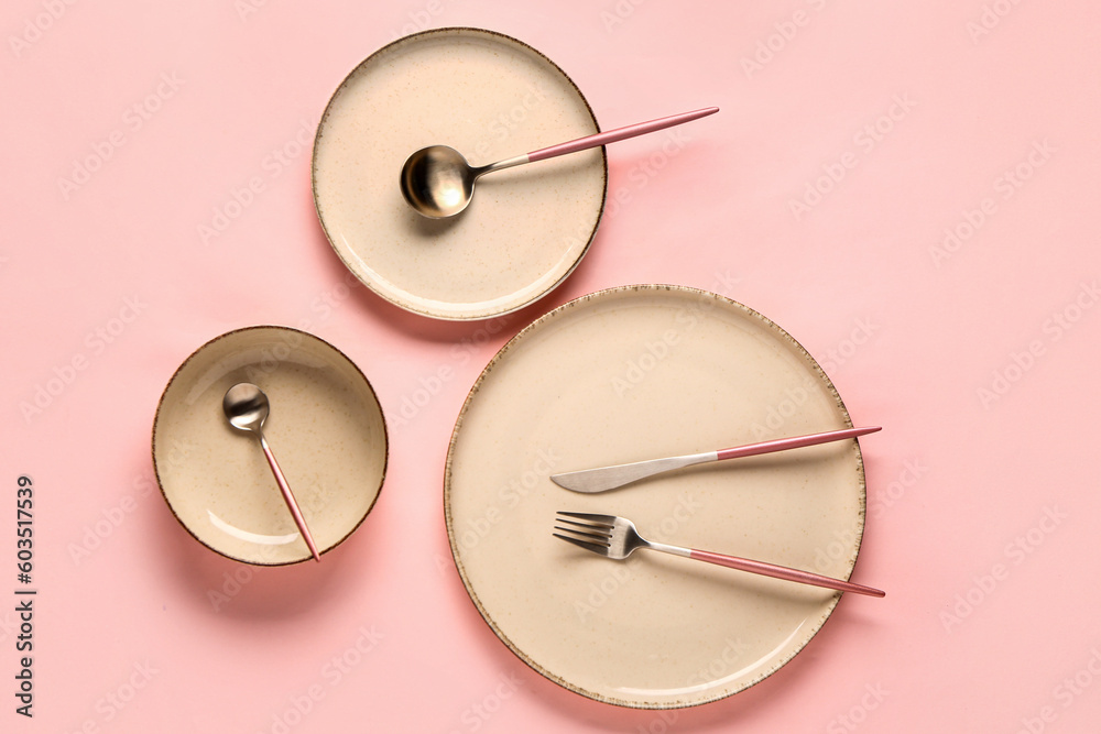Table setting with clean plates and cutlery on pink background Table setting with clean plates and cutlery on pink background