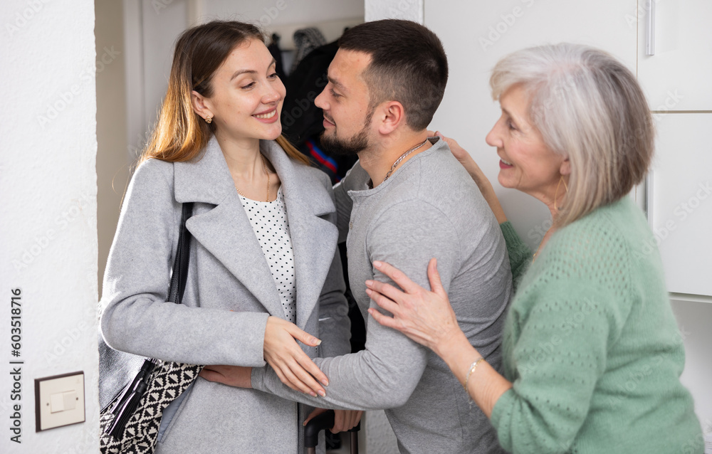 Fototapeta premium Husband and an elderly mother are happy to meet her young wife at home