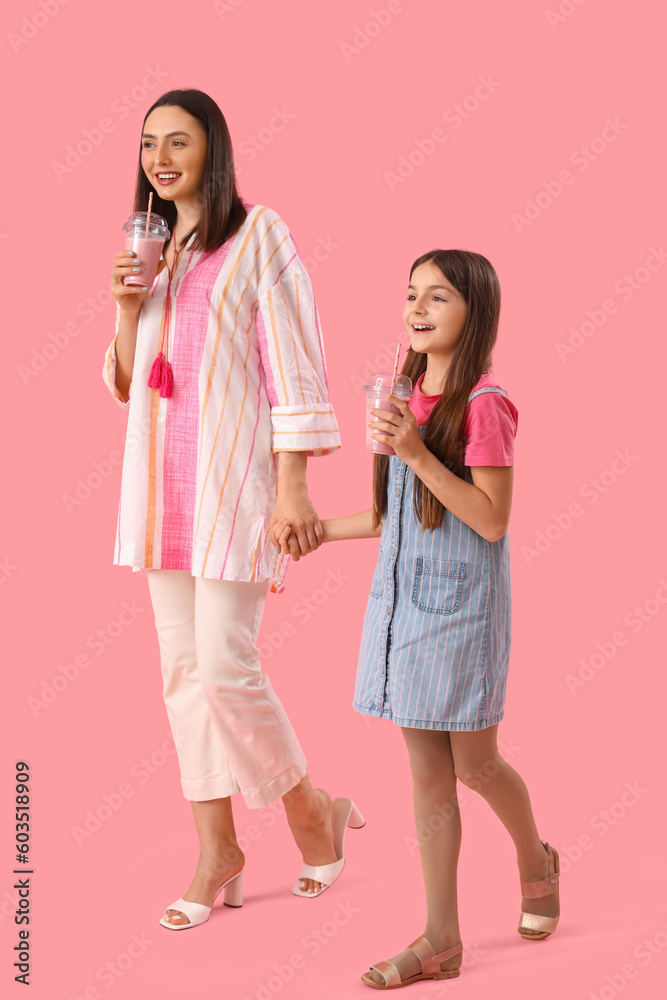 Little girl with her mother drinking smoothie on pink background Little girl with her mother drinking smoothie on pink background