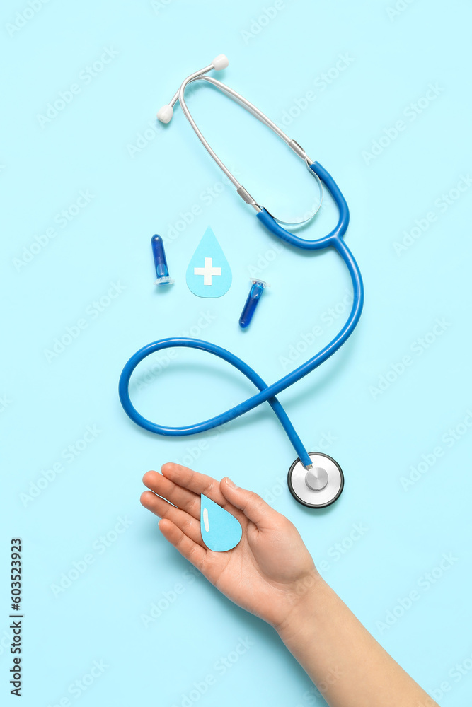 Woman with paper drops, test tubes and stethoscope on blue background. World Blood Donor Day Woman with paper drops, test tubes and stethoscope on blue background. World Blood Donor Day