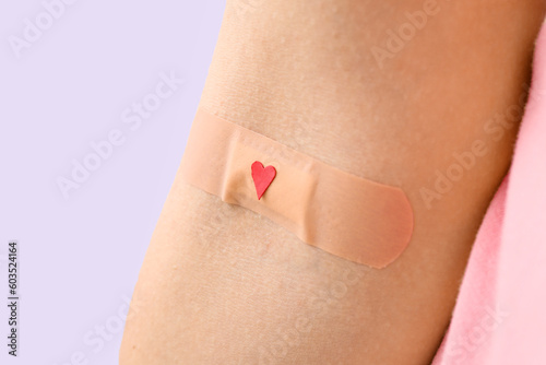 Woman with applied medical patch on lilac background, closeup. World Blood Donor Day © Pixel-Shot
