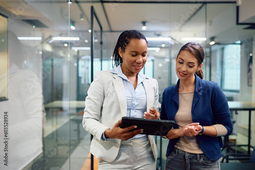 Smiling businesswomen cooperating while using touchpad in office.