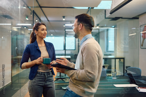 Young colleagues talk during coffee break in office.