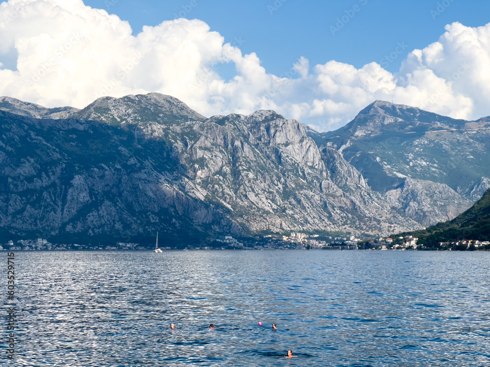 People swim in the bay against the backdrop of a high mountain range
