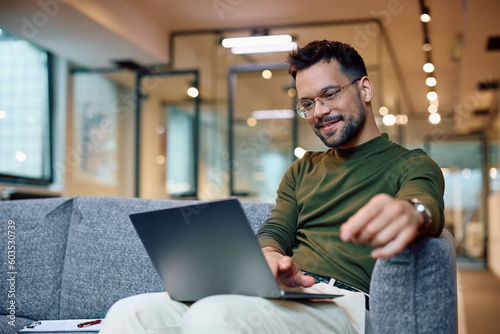 Canvas Print Smiling entrepreneur reading an email on laptop in office.