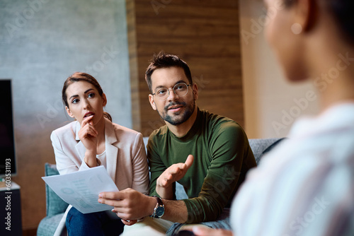 Young couple communicating with insurance agent while analyzing documents during meeting.