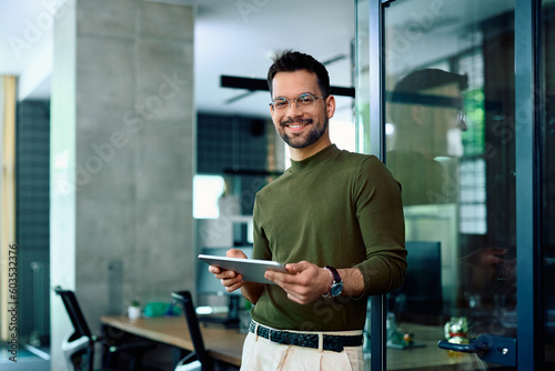 Happy entrepreneur using digital tablet in office and looking at camera. photo