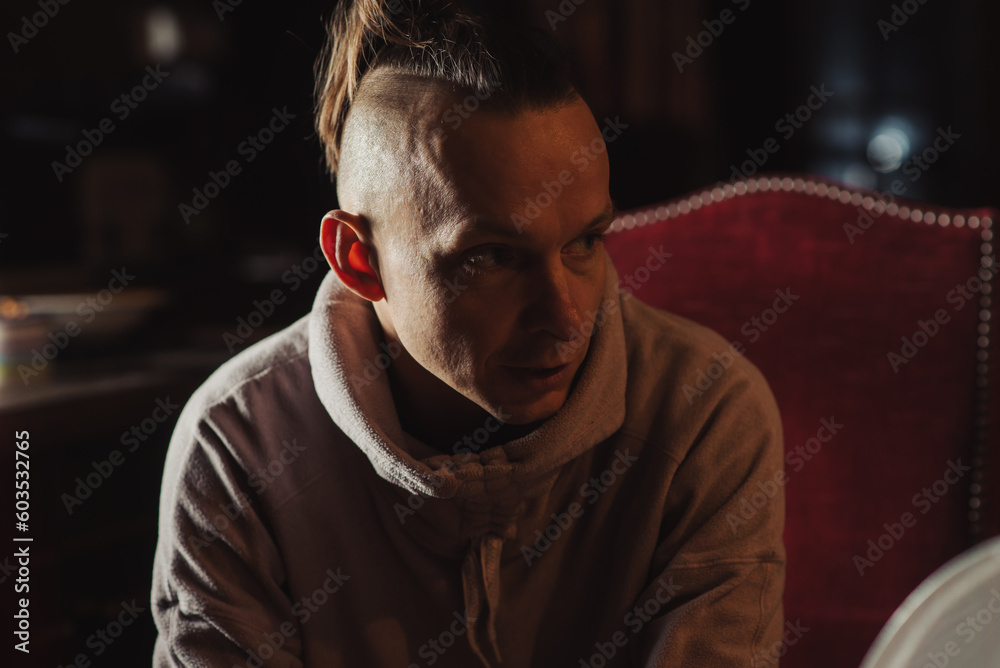 Obraz premium Middle-aged man in a dark room. Ordinary man of thin build.
