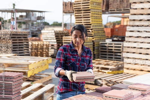 Woman places paving slabs on a pallet in a building materials warehouse