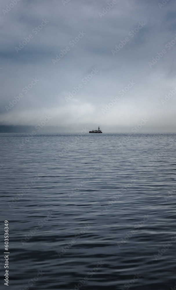 A boat on the water with hazy clouds
