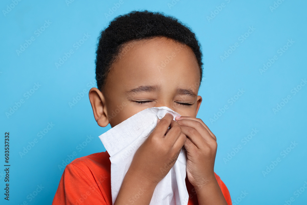 African-American boy blowing nose in tissue on turquoise background. Cold symptoms African-American boy blowing nose in tissue on turquoise background. Cold symptoms