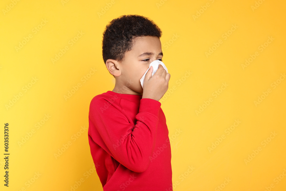 African-American boy blowing nose in tissue on yellow background, space for text. Cold symptoms African-American boy blowing nose in tissue on yellow background, space for text. Cold symptoms