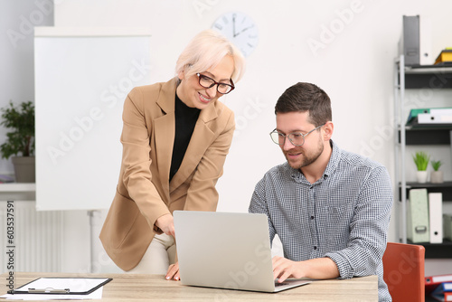Boss and employee with laptop discussing work issues in office