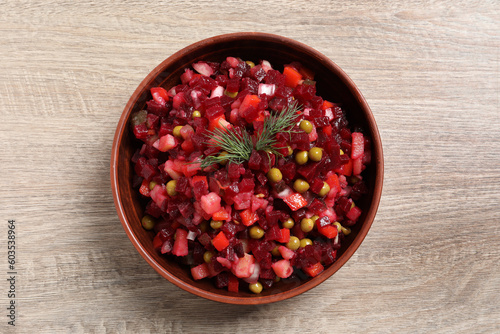 Bowl of delicious fresh vinaigrette salad on wooden table, top view