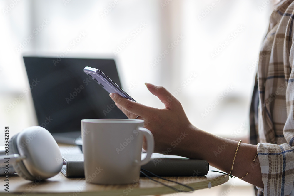 Pleasant young asian woman sitting in living room interior and chatting online on mobile phone. Pleasant young asian woman sitting in living room interior and chatting online on mobile phone.