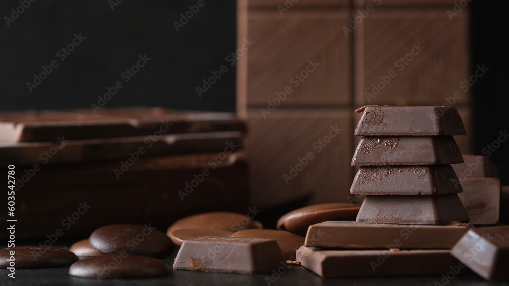 Stack of milk chocolate and dark chocolate bars on black background. Dessert food background. Stack of milk chocolate and dark chocolate bars on black background. Dessert food background.