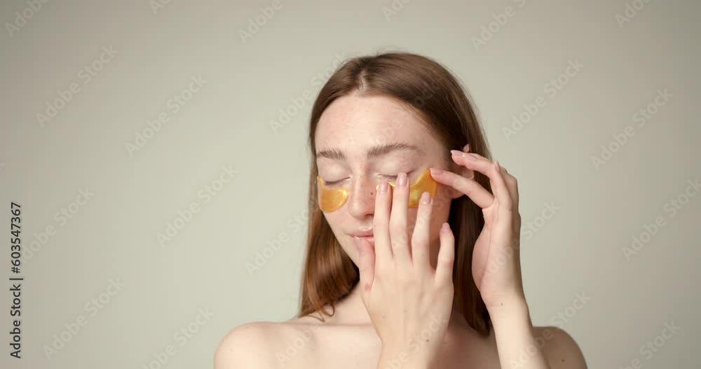 Ginger haired young lady applying skin care on face Ginger haired young lady applying skin care on face