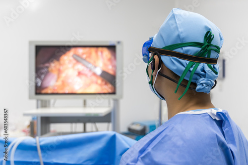 Doctor or surgeon in blue uniform looking at monitor screen in operating room at hospital.Minimal invasive gall bladder surgery in stone.Medical technology with white space.Computer assist device.