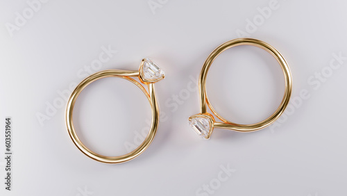 Top view of two gold rings with square diamonds on white background from design with 3d render.