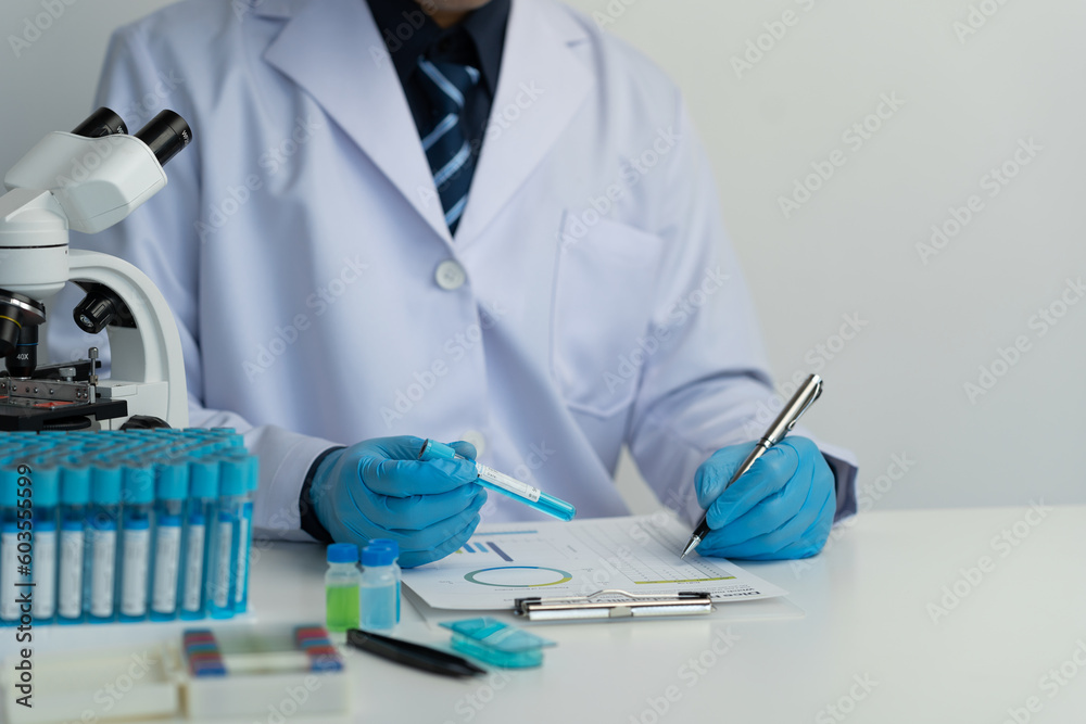 Male scientist using scientific test tubes with data recording of chemicals or drugs tested and examined by microscope in science laboratory for medicine biotechnology biology. Male scientist using scientific test tubes with data recording of chemicals or drugs tested and examined by microscope in science laboratory for medicine biotechnology biology.