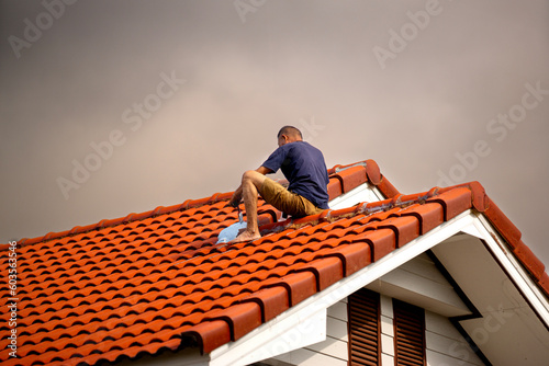 Phayao  Thailand  May 3 2023  roofing contractor Seal the roof leaks with  sealant in the rainy season  on the backdrop of the sky in the rainy season