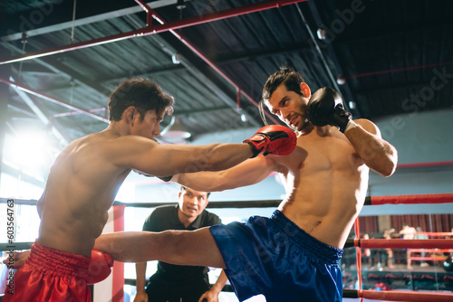 Two professional boxers are fighting on boxing ring, sportsmen boxing in the fight on square stage, or sport exercising with trainer at boxing and self defense lesson studio background, Thai Box match © chokniti