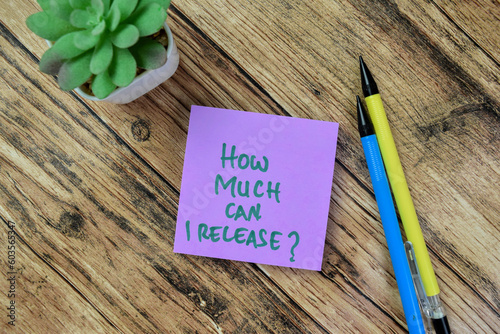 Concept of How Much Can I Release? write on sticky notes isolated on Wooden Table.