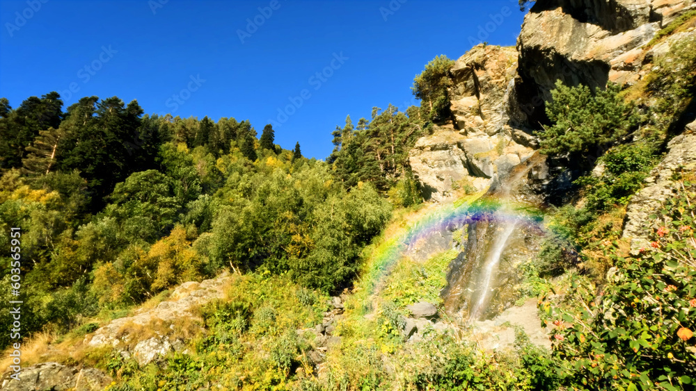 mountain forest waterfall with rainbow at summertime, tourer experience - photo of nature