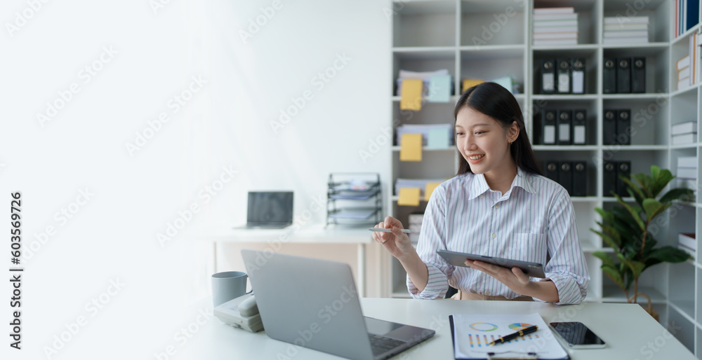 Consultant, advisor, Asian business woman working on the tablet computer work financial and marketing business plan to increase company profits, ready to use computer and marketing planning documents