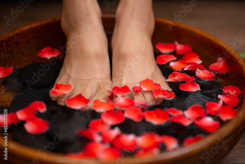Woman soaks her feet in a bowl with flower petals