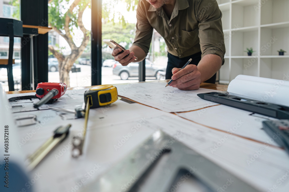 engineer checks construction blueprints on new project with engineering tools at desk in office engineer checks construction blueprints on new project with engineering tools at desk in office