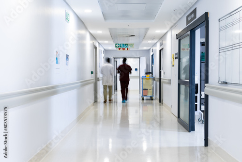Blurred motion of diverse doctors walking in busy hospital corridor  copy space