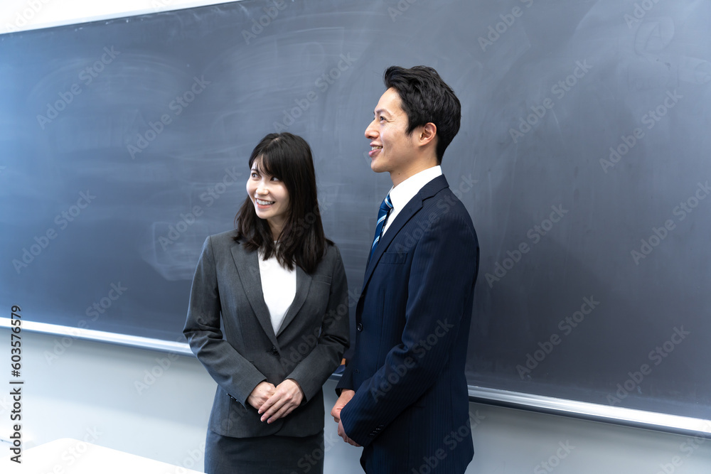 学校の黒板の前に立つ2人の先生