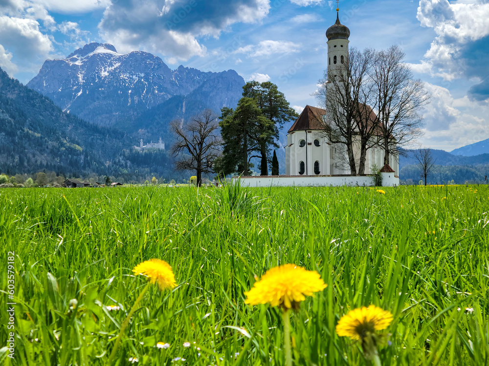 Meadow and beautiful old church in Bavaria with Neuschwanstein Castle and Bavarian Alps in distance - Fussen, Germany	