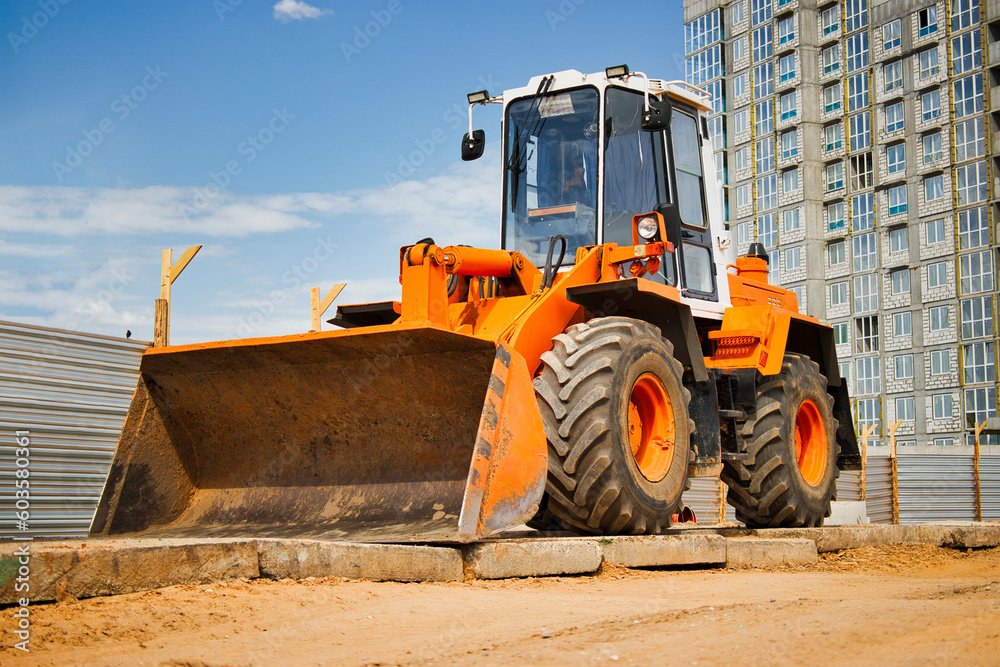 Fototapeta premium Heavy front loader or bulldozer at the construction site. Construction equipment. Transportation and movement of bulk materials. Rental of construction equipment.