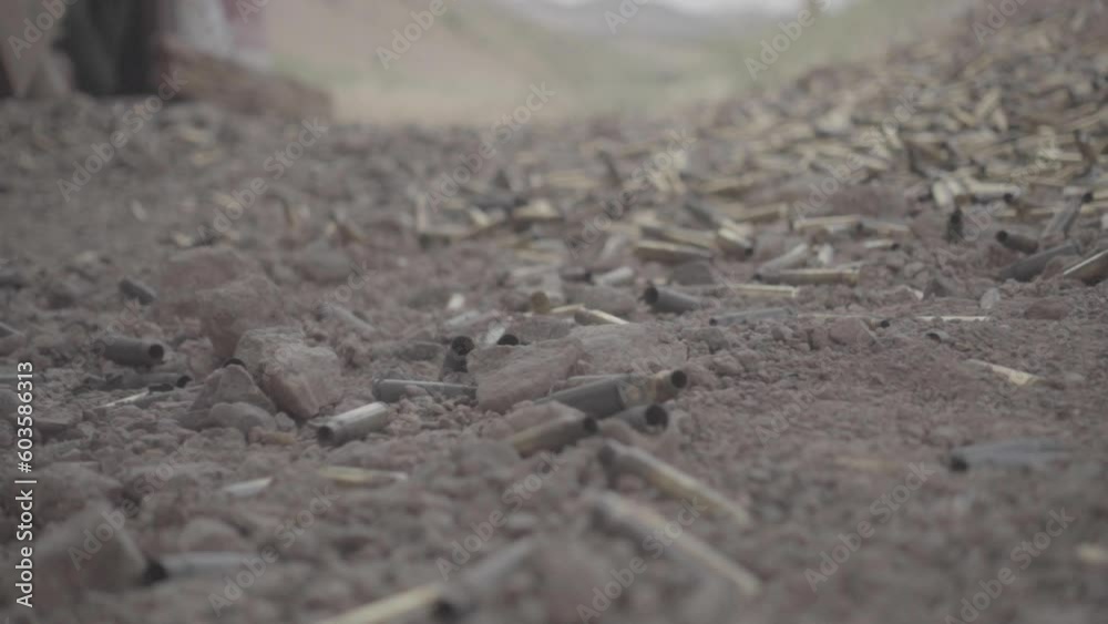 Giant bullet shell falling on the ground in slowmotion on sand that's covered in bullet shells on a shooting range in USA America LOG Giant bullet shell falling on the ground in slowmotion on sand that's covered in bullet shells on a shooting range in USA America LOG