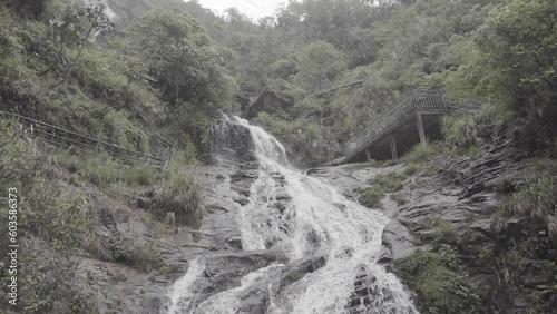 Slowmotion shot of water coming down of a waterfall in Vietnam on a rainy and cloudy day in between plants and trees in nature LOG photo