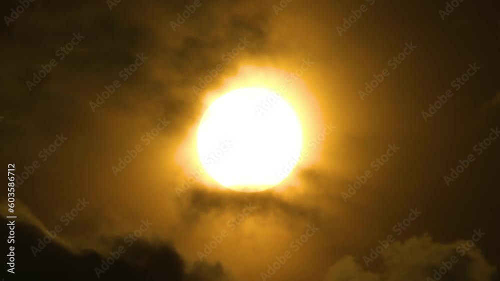 Dark clouds pass across glowing orange sun over dark sky. Static detail shot Dark clouds pass across glowing orange sun over dark sky. Static detail shot