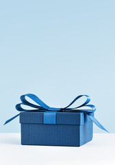 small Luxury gift box with a blue bow on light blue. Side view monochrome . Fathers day or Valentines day gift for him. Corporate gift concept or birthday party. Festive sale copy space