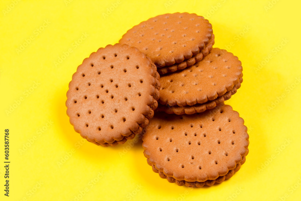 A pile of round cookies stuffed on a yellow background. Sweet biscuits filled with cocoa. A pile of round cookies stuffed on a yellow background. Sweet biscuits filled with cocoa.