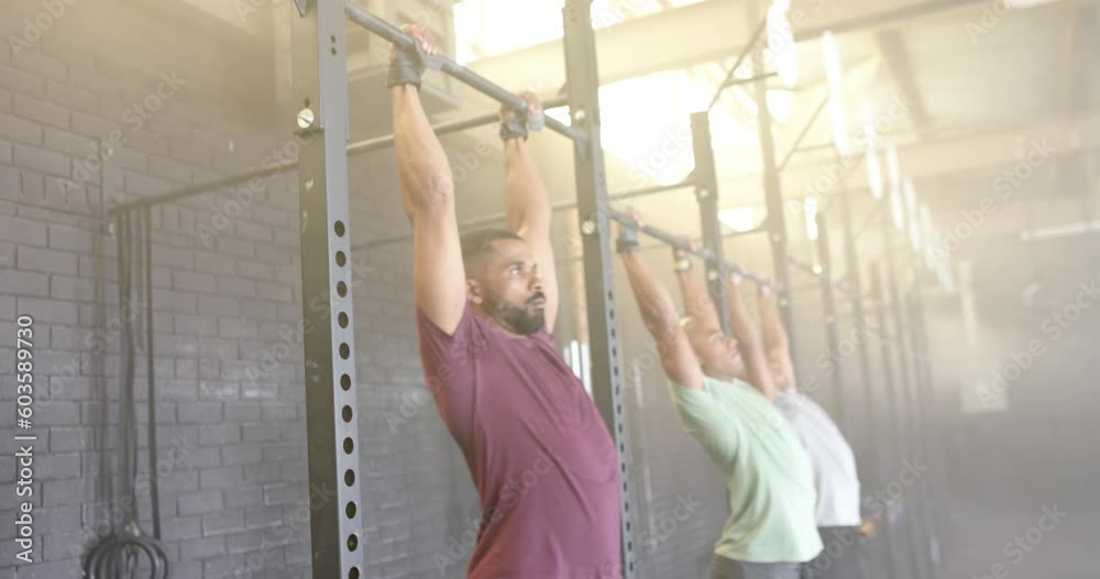 Diverse male group fitness class training at gym doing pull ups on bars, in slow motion