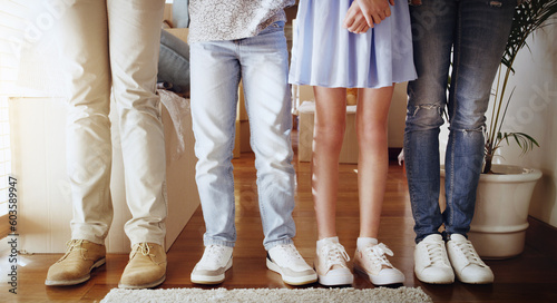 Love, family and closeup of people with shoes standing in a line in the living room of their home. Bonding, together and zoom of couple and children legs in a row in the lounge of their modern house. photo