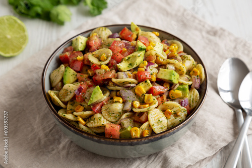 Homemade Grilled Corn Summer Pasta Salad in a Bowl on a white wooden background, low angle view.