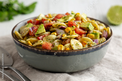 Homemade Grilled Corn Summer Pasta Salad in a Bowl on a white wooden background, low angle view. Close-up.