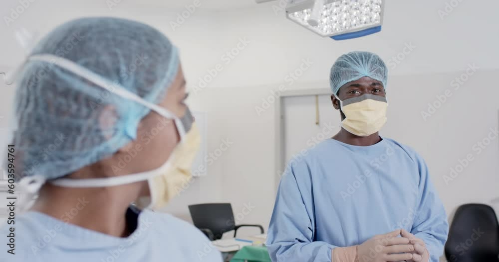 Portrait of happy diverse surgeons with face masks in operating room in slow motion, unaltered Portrait of happy diverse surgeons with face masks in operating room in slow motion, unaltered