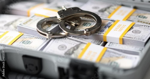 Metal handcuffs on dollar bills packs in open briefcase. Criminal responsibility for illegal financial operations. Theft arrest and money confiscation photo