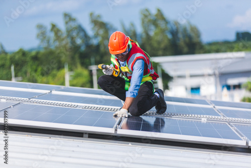 Male professional engineer installing solar photovoltaic panel system, Electrician mounting blue solar module technology on power industrial factory roof, Alternative energy ecological technician job