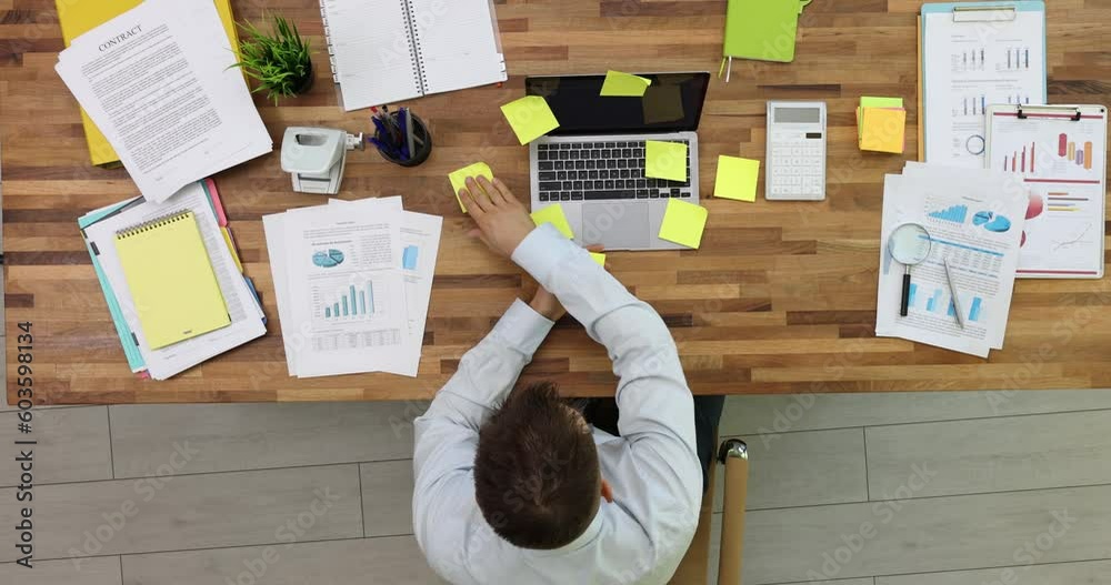 Businessman puts bright memo stickers on laptop and desk in office ...