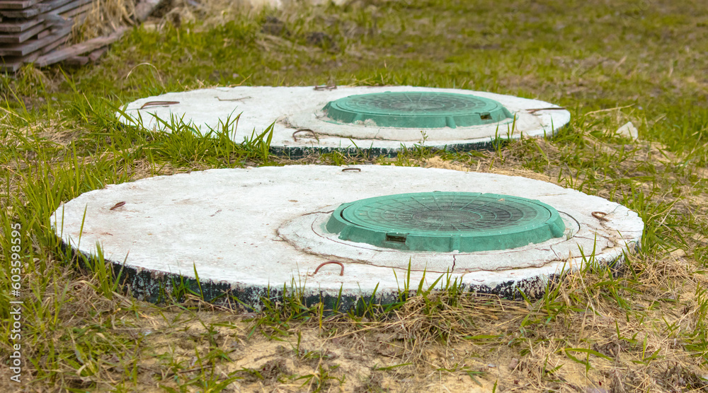 Naklejka premium Green manhole cover on the grass in the park.
