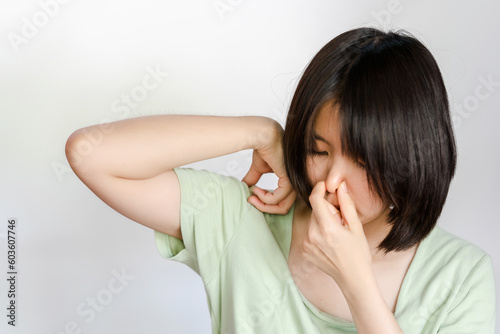 A woman covers her nose with her hand because of the smell of sweat coming from the armpits.
